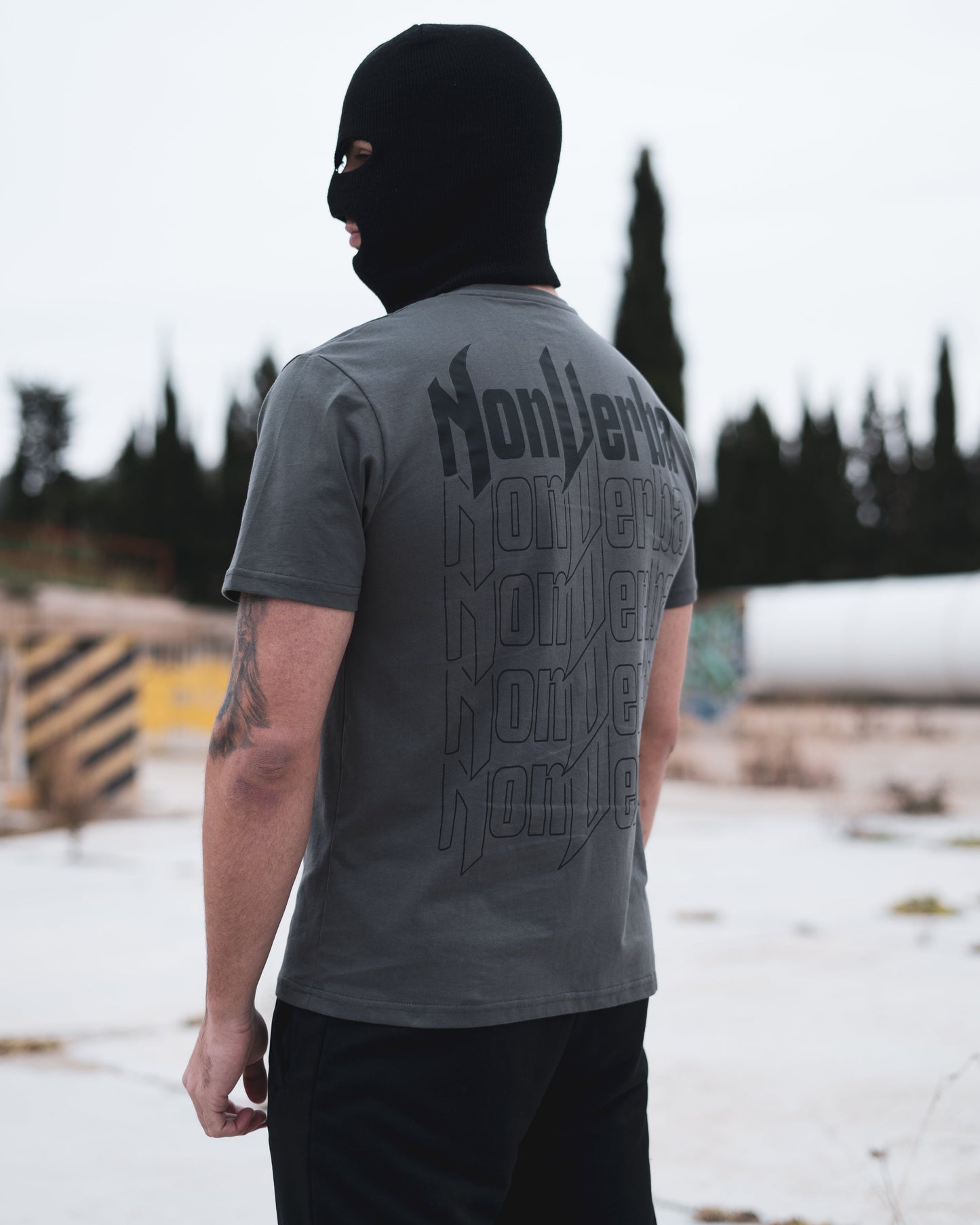 Modelo de costado en una zona abandonada con la camiseta gris de la marca NonVerba.