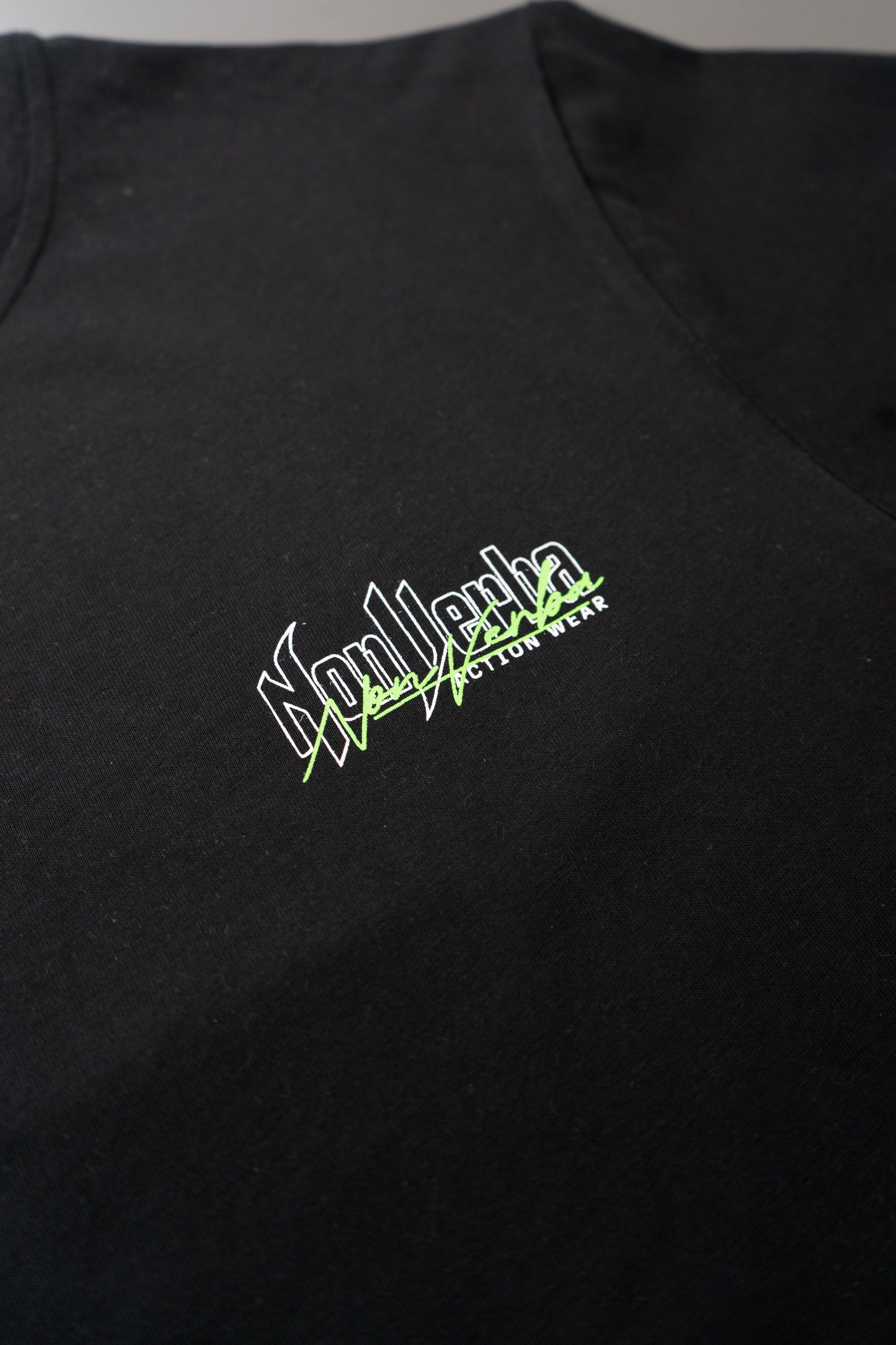 Logotipo de NonVeba situado en la parte superior izquierda del pecho de la camiseta negra de NonVerba.