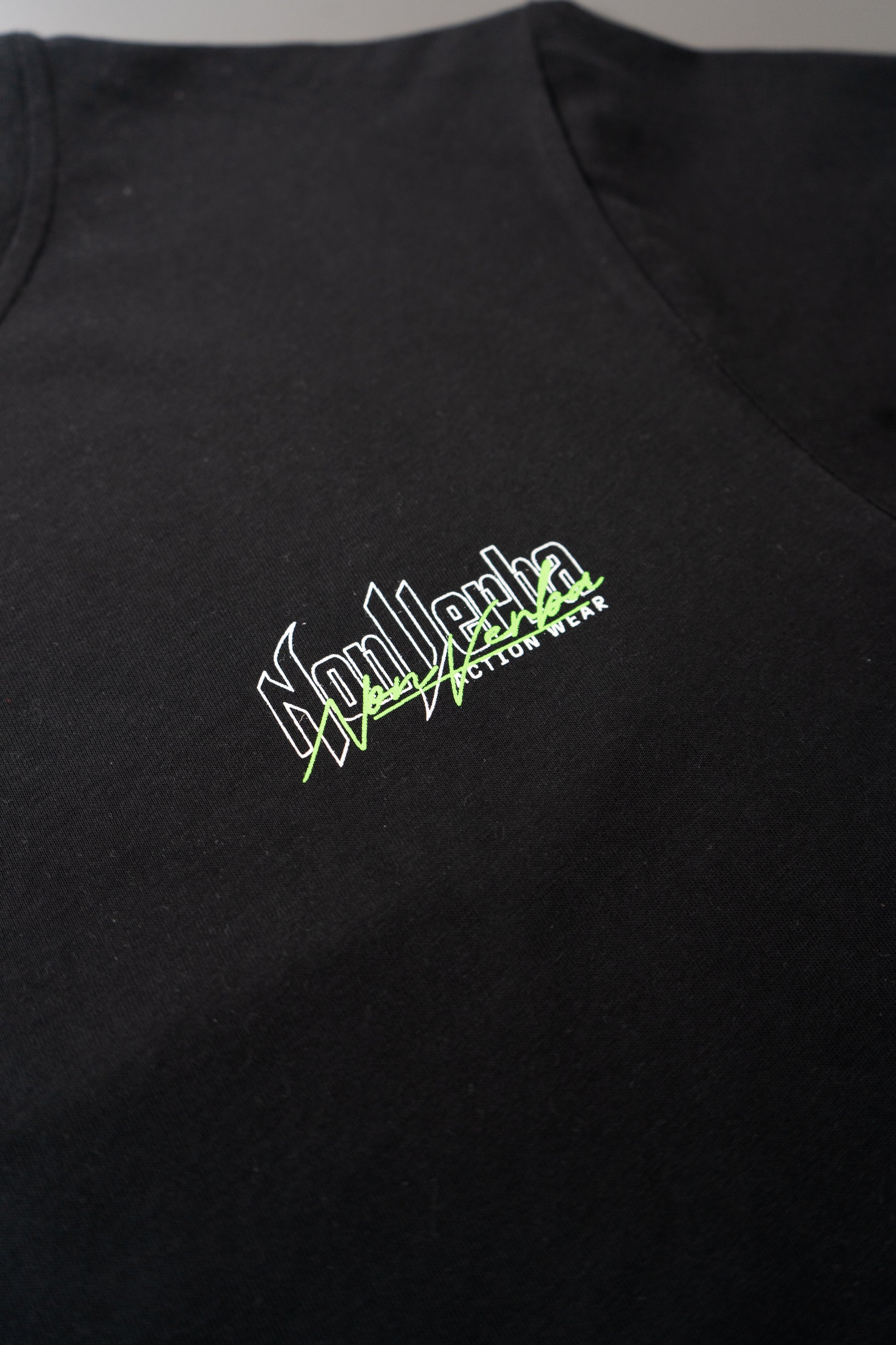 Logotipo de NonVeba situado en la parte superior izquierda del pecho de la camiseta negra de NonVerba.