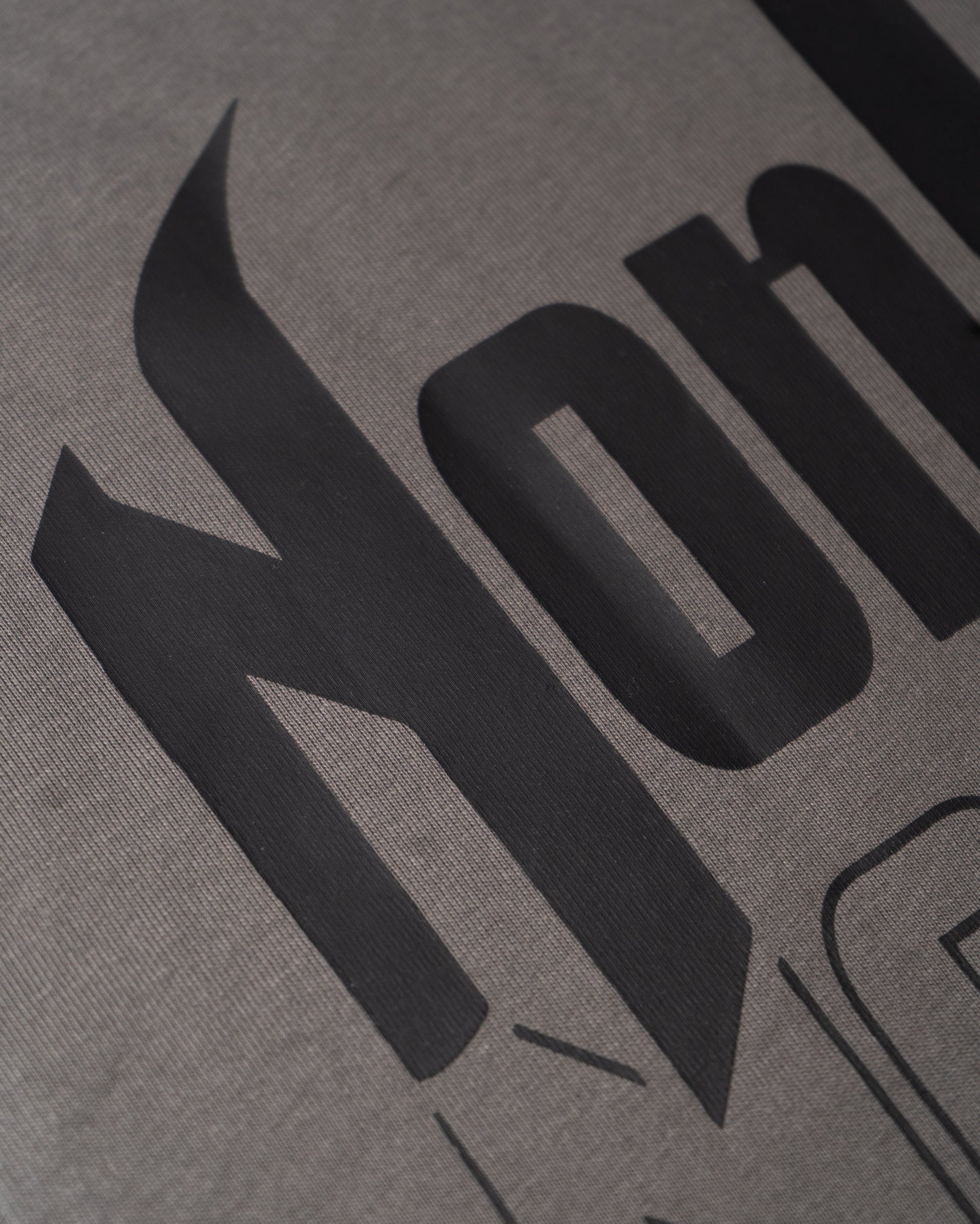 Imagen cercana de la etiqueta de la parte trasera de la camiseta gris de NonVerba.